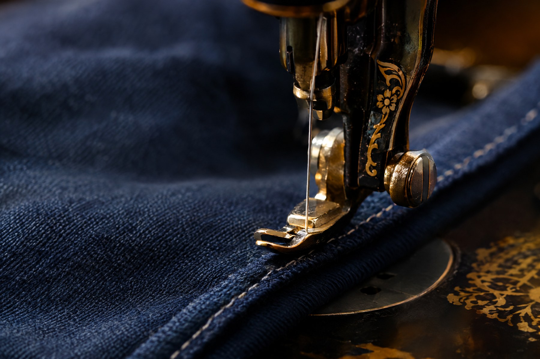 Machine à coudre piquant une couture sur un tissu indigo